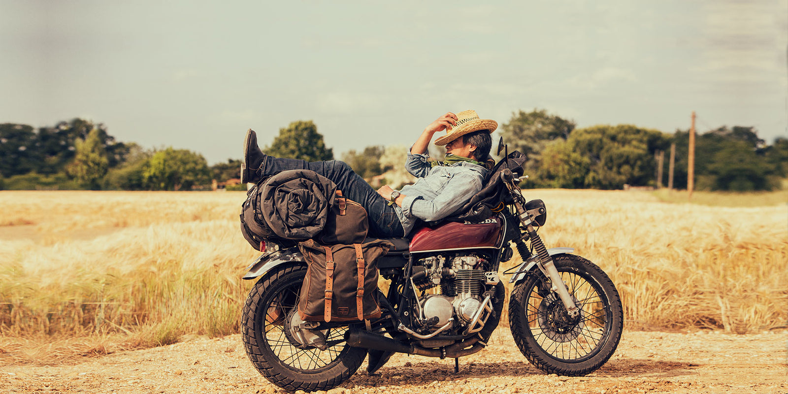 Biker sleeping on retro motorcycle with soft saddlebags.