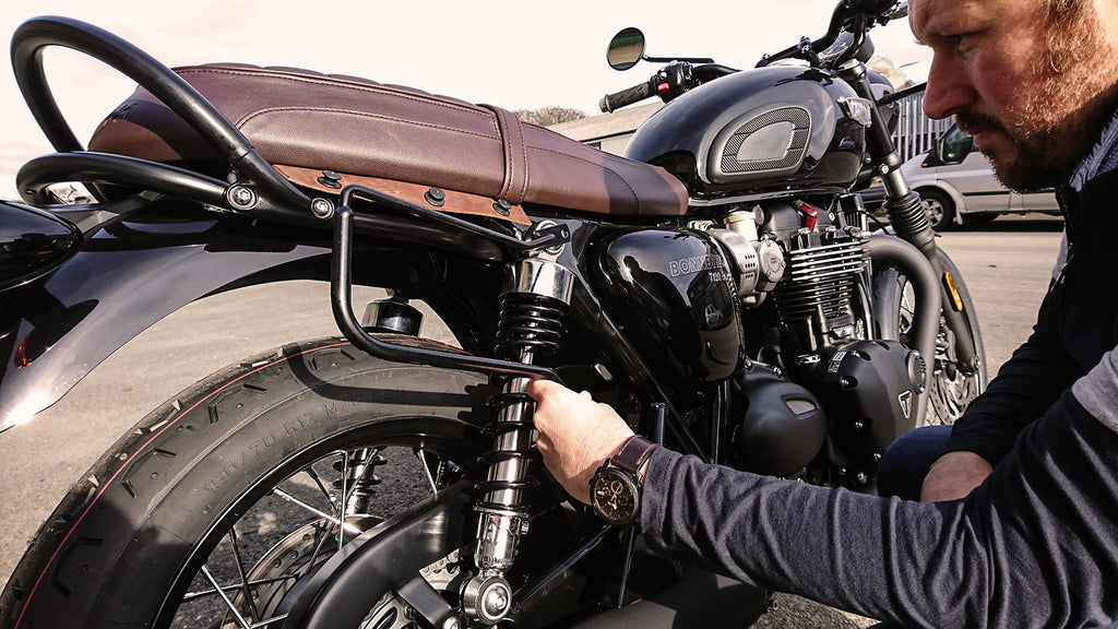 Man fitting black spacer on the Bonneville T120.
